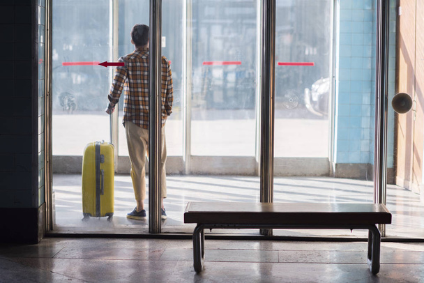 вид сзади стильного туриста-мужчины с колёсной сумкой на станции метро
  - Фото, изображение
