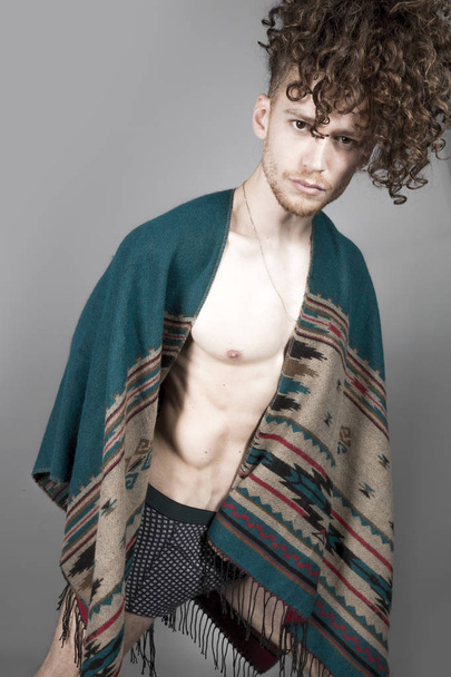 Young athletic ginger man in pancho studio portrait - Фото, изображение