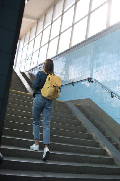 rear view of female tourist with backpack going upstairs at subway - Valokuva, kuva