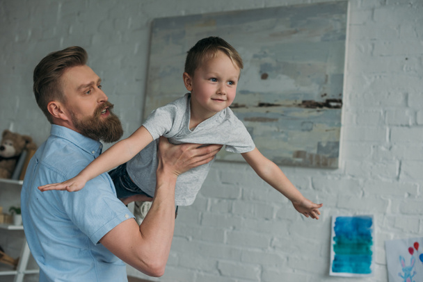портрет отца, веселящегося вместе с маленьким сыном, проводящего время дома
 - Фото, изображение