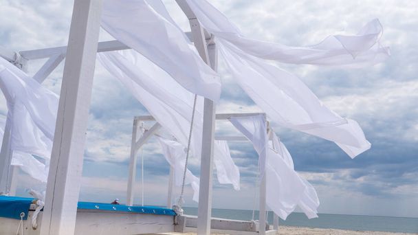 Sheds  awning with fabric white curtains on the seashore breeze in the wind - Photo, Image