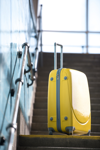 closeup shot of yellow wheeled bag on stairs at subway  - 写真・画像