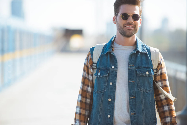 stijlvolle mannelijke toerist in zonnebril met rugzak op buiten metrostation - Foto, afbeelding