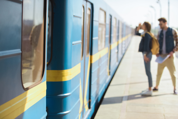 closeup shot of train and couple of tourists behind at outdoor subway station  - Фото, зображення