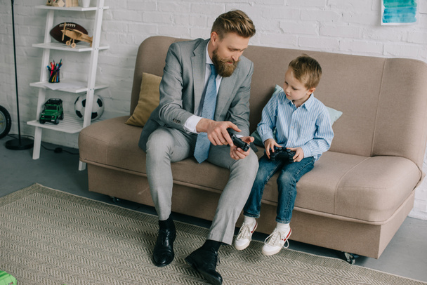 businessman and little son playing video games together at home, work and life balance concept - Foto, Bild