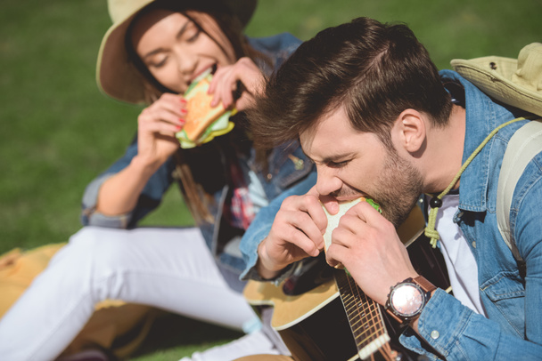 couple of stylish travelers with guitar eating sandwiches  - Photo, Image