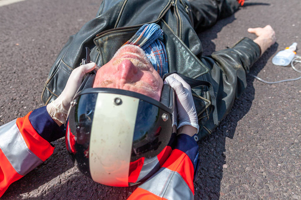 Немецкий парамедик снимает шлем с травмированного байкера. Мбаппе - немецкое слово для скорой помощи
. - Фото, изображение