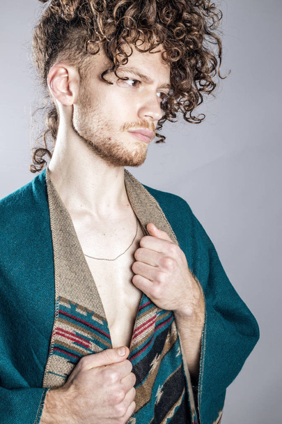 Young athletic ginger man in pancho studio portrait - 写真・画像