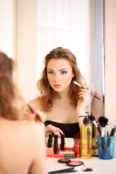 Young beautiful woman making make-up near mirror - Fotoğraf, Görsel