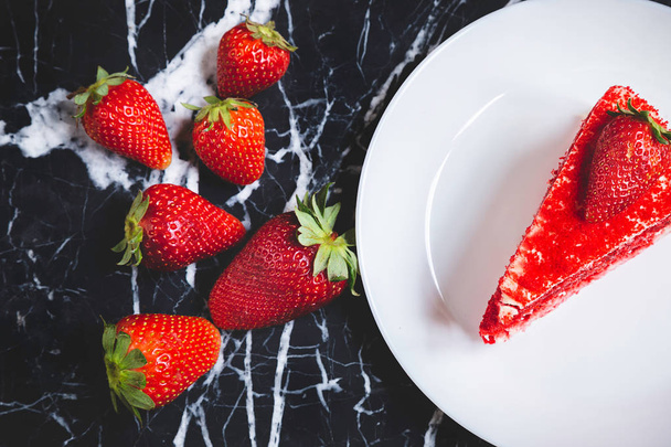 Punainen sametti kakku mansikoita marmoripöydässä
 - Valokuva, kuva