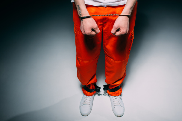 Oříznutý pohled člověka nošení oranžové kalhoty do manžety na tmavém pozadí - Fotografie, Obrázek
