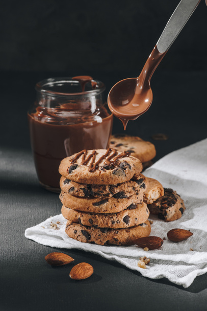close-up shot of liquid chocolate pouring onto stacked chocolate-chip cookies - Фото, зображення