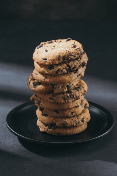 stack of delicious chocolate-chip cookies on black plate - Photo, Image