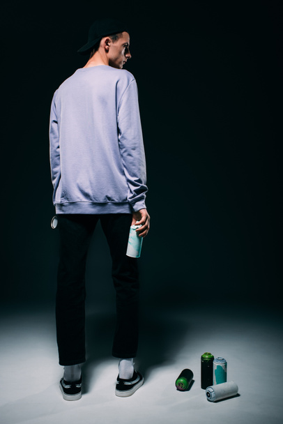 Handsome man standing with spray paint on dark background - Фото, зображення