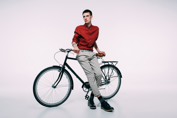 Young man leaning on his bicycle on white background - Fotoğraf, Görsel