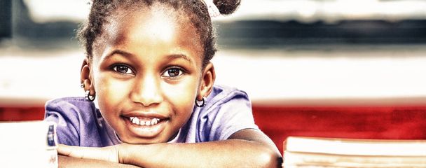 Boldog afrikai lány az iskolában, a pultnál. - Fotó, kép