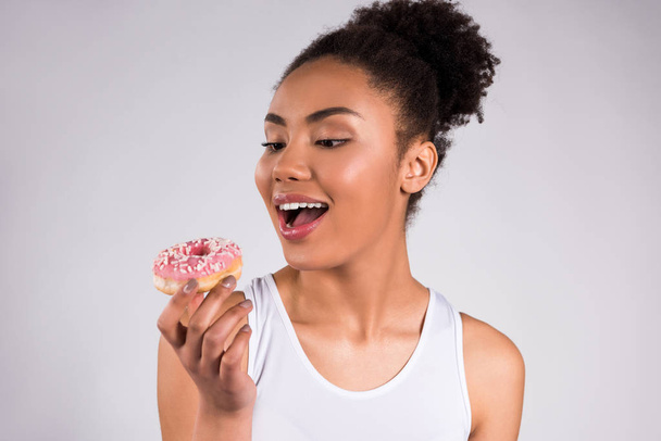 African American girl eating donut isolated. - Foto, immagini