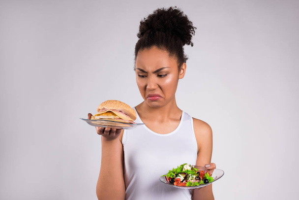 Černá dívka drží cheeseburger a salát, samostatný - Fotografie, Obrázek