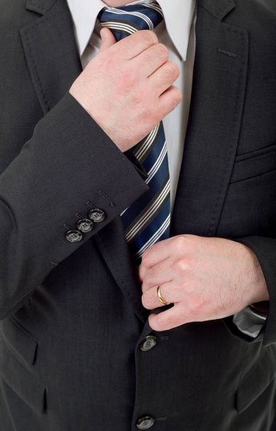 бизнесмен в черном костюме регулирует галстук
 - Фото, изображение