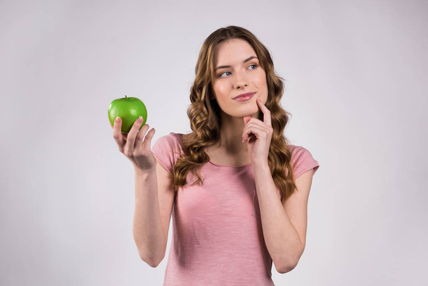 Girl playfully holding green apple isolated. - Zdjęcie, obraz