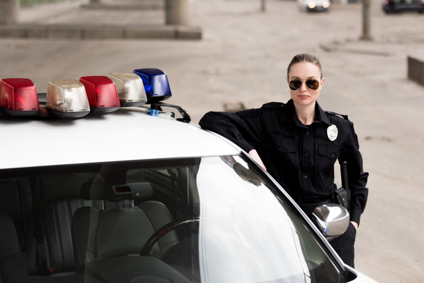 female police officer leaning on patrol car - Фото, зображення