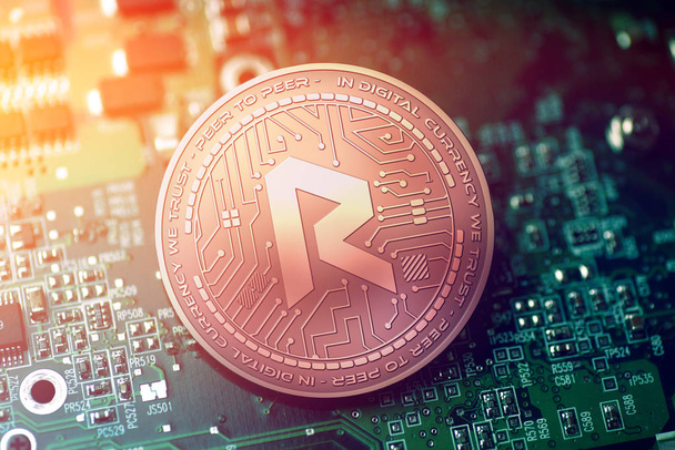 shiny copper REVAIN cryptocurrency coin on blurry motherboard background - Photo, Image