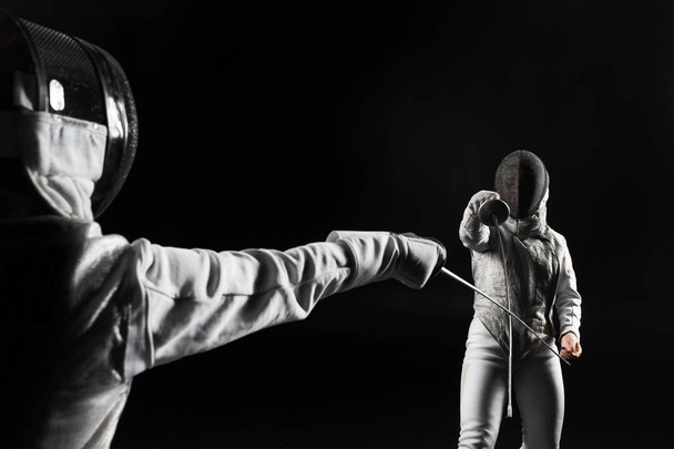 two fencers fighting on black background - Foto, Imagen