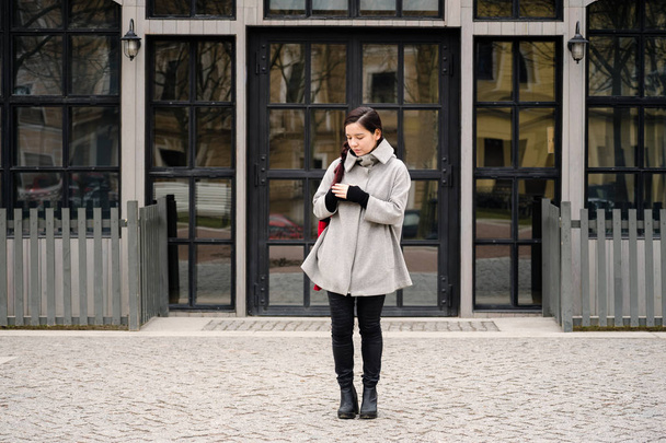 asian woman dressed in gray coat and high-heeled boots walking at street during springtime - Fotoğraf, Görsel