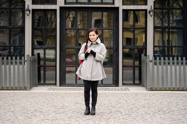 asian woman dressed in gray coat and high-heeled boots walking at street during springtime - Foto, Imagen