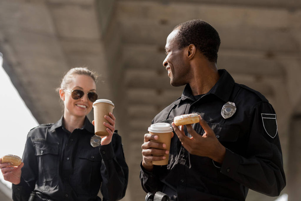 молодые офицеры полиции делают перерыв на кофе с пончиками
 - Фото, изображение