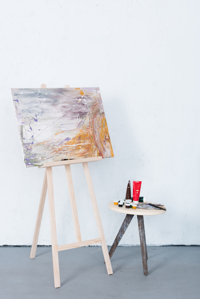 painting on easel and paints on stool in creative workshop - Zdjęcie, obraz