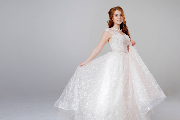 Lovely young woman bride in lavish wedding dress. Light background. - Photo, Image