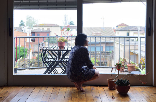 una donna triste che guarda fuori dalla finestra a casa
 - Foto, immagini