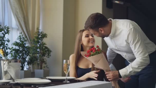 Happy girlfriend is getting flowers and present from her boyfriend after waiting for him alone in restaurant. Romantic relationship, gifts and fine dining concept. - Metraje, vídeo