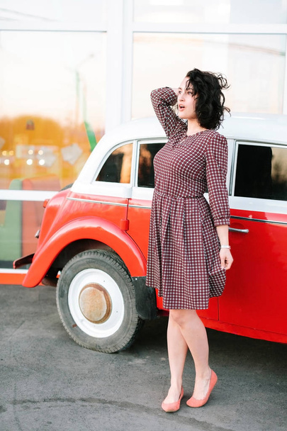 emotions, vintage, lifestyle concept. by the old fashioned car in white and red coloures there is a marvelous woman who looks a bit embarassed and as she forgot something important - Φωτογραφία, εικόνα