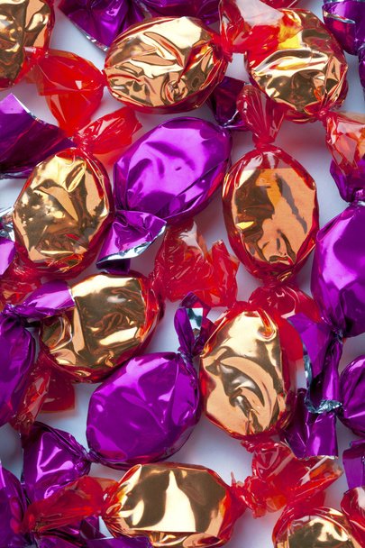 doces duros dourados e roxos envoltos em envoltório de doces brilhantes
 - Foto, Imagem