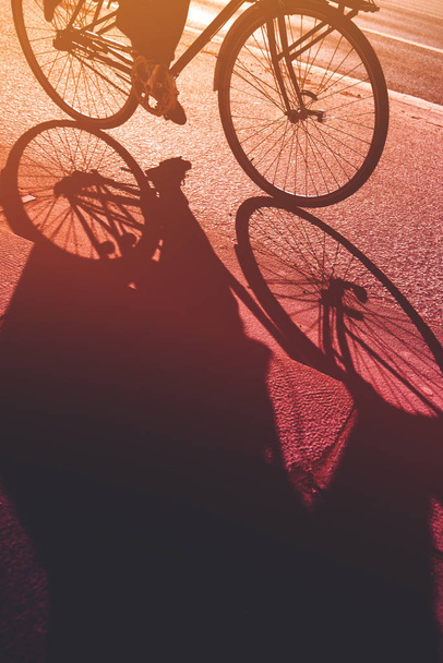 Shadow of unrecognizable person riding bicycle - Fotoğraf, Görsel