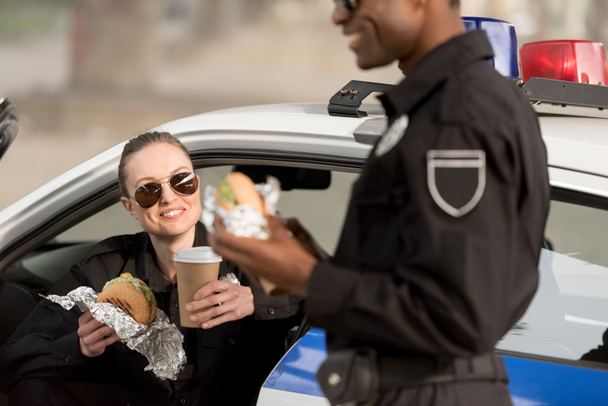 plan recadré d'un policier afro-américain déjeunant avec une policière tenant une tasse de café
 - Photo, image