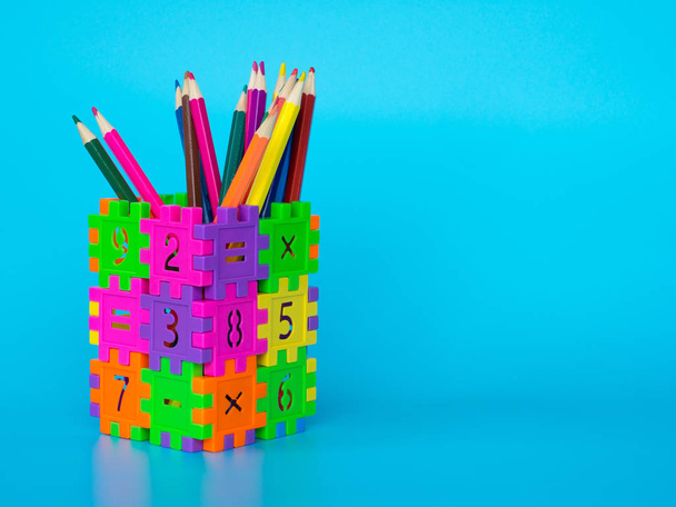 Кольорові олівці в барвистому тримачі для олівців утворюють номер головоломки на синьому фоні. Концепція освіти. копіювати простір для тексту і вмісту
. - Фото, зображення
