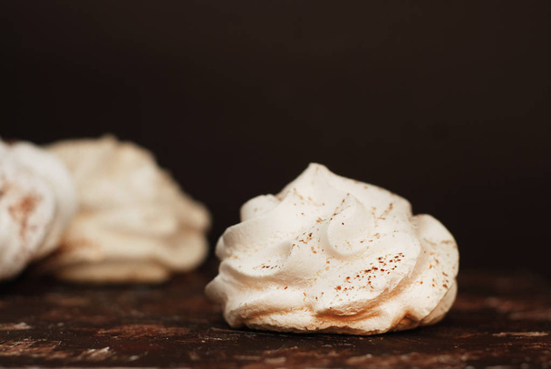 White Meringue Cookies. Sweet Desert over Brown Rusty Wooden Board in Black Plate. - Photo, image