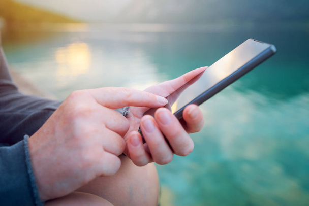 Жінка використовує мобільний телефон на відкритому повітрі в природі
 - Фото, зображення