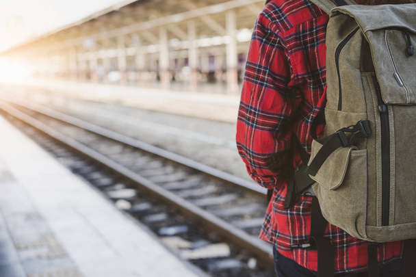 Young Asian woman backpacker traveler walking alone at train station platform with backpack. Asian woman waiting train at train station for travel. Summer holiday traveling or young tourist concept. - Photo, Image