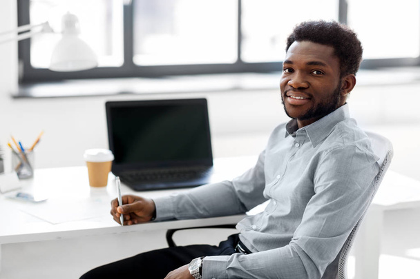 Αφρικανικός Αμερικανός επιχειρηματίας με στυλό στο γραφείο - Φωτογραφία, εικόνα