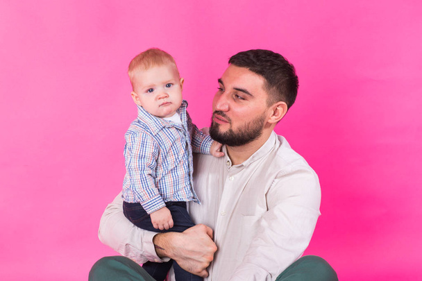 Ευτυχισμένος πορτρέτο του πατέρα και γιο σε ροζ φόντο. Στο studio - Φωτογραφία, εικόνα