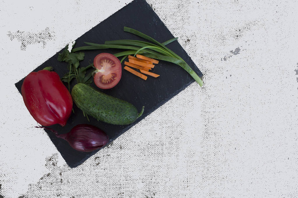 friss zöldség, bors, uborka, hagyma, paradicsom a konyhaasztalon - Fotó, kép