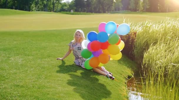 Slow motion beelden van mooie jonge vrouw poseren met kleurrijke ballonnen door de rivier - Video
