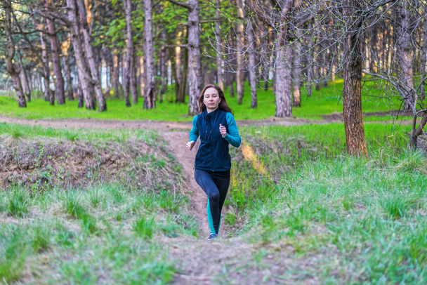 Young woman on a morning run through the spring forest. - Фото, зображення