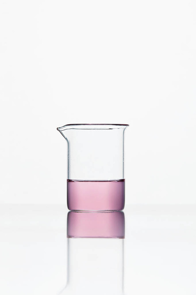 Лабораторний скляний посуд. Скло з рожевою рідиною на білому тлі
 - Фото, зображення