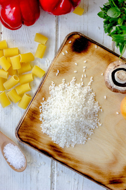 Vue du dessus du riz blanc sec sur la planche de cuisine avec des légumes autour
 - Photo, image