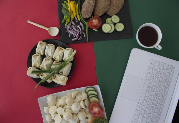 laptop computer, zelfgemaakte dumplings met vlees, groenten, kopje koffie op tafel - Foto, afbeelding